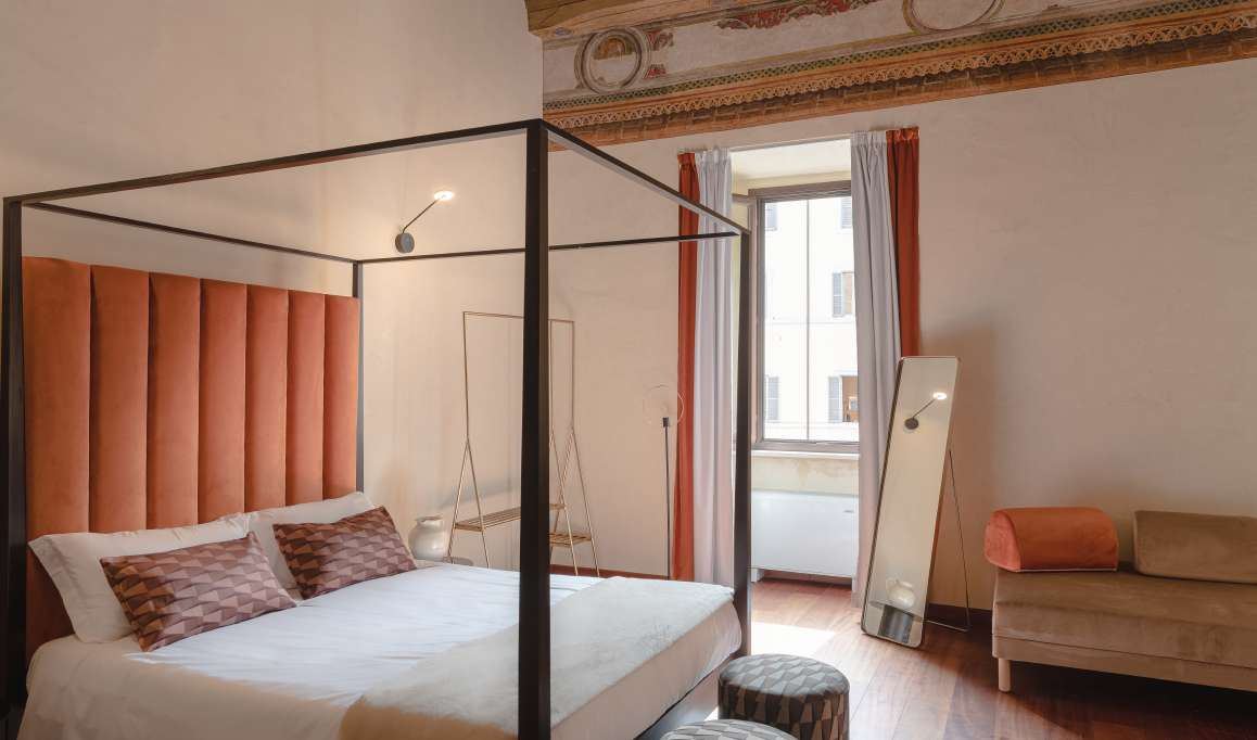 Room with a canopy bed and a frescoed frieze