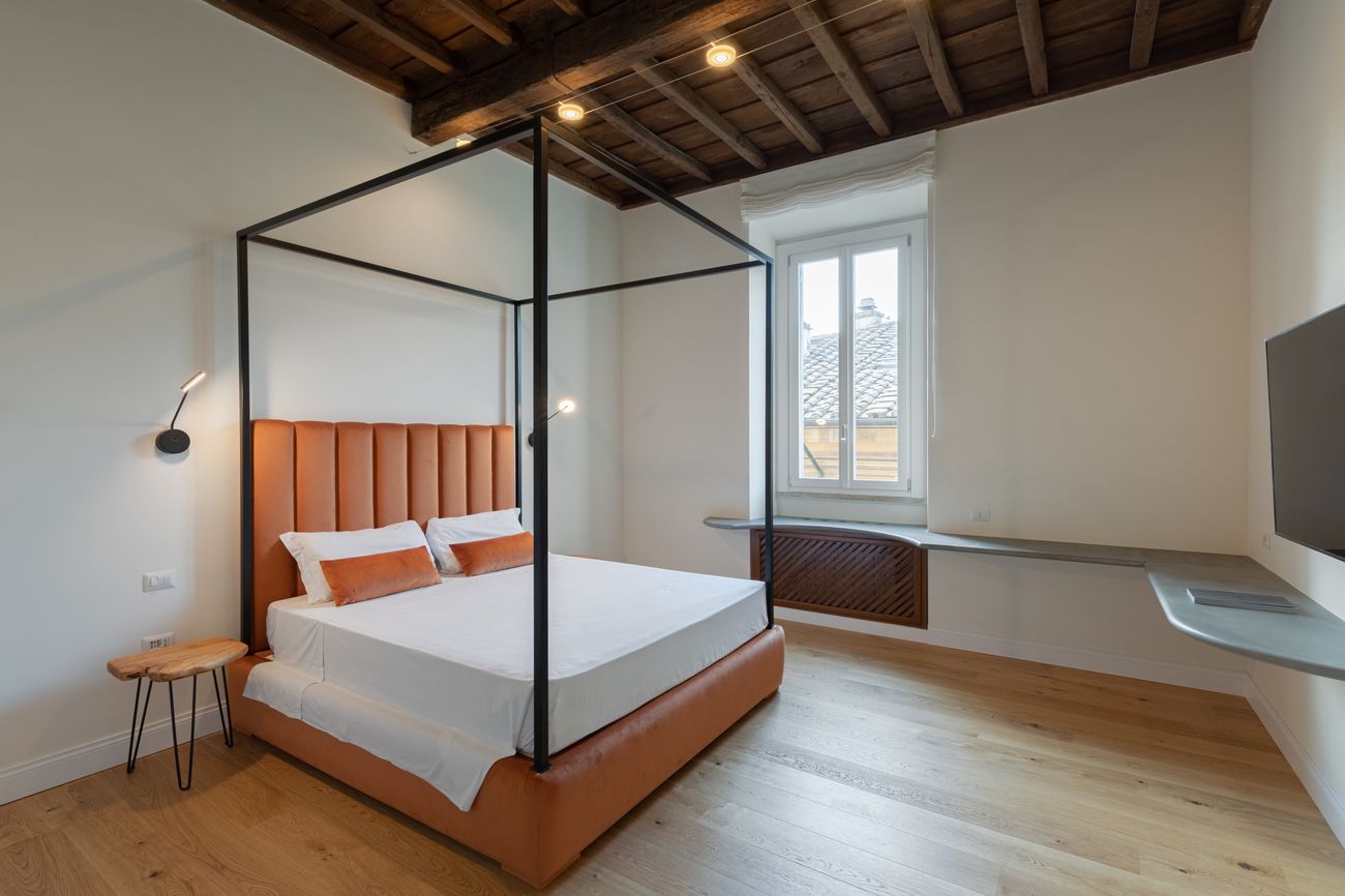 Bedroom with a canopy bed, a velvet headboard and a beamed ceiling