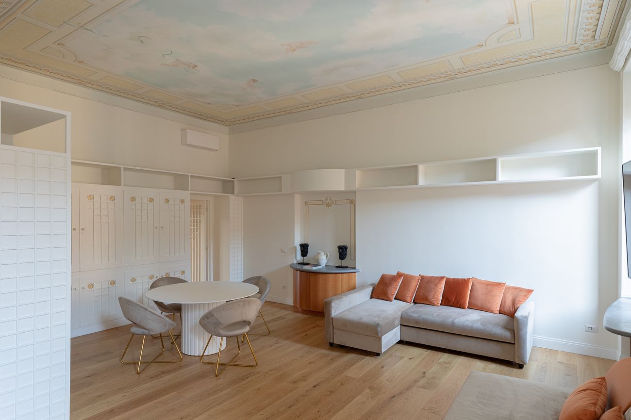 Living room with a frescoed ceiling, bespoke shelving and a velvet sofa